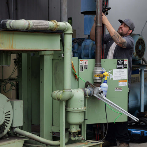 Advanced Air & Vacuum technician installing a Sullair rotary screw air compressor at an industrial facility.