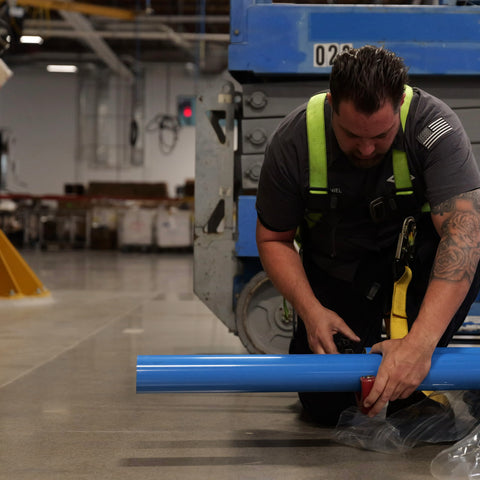 Technician cutting blue aluminum piping for compressed air system installation