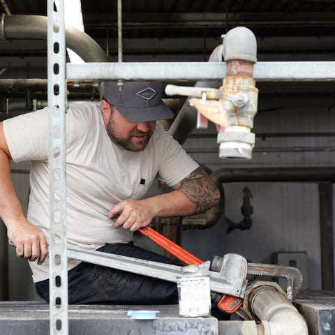 Advanced Air & Vacuum technician installing industrial air compressor piping during a compressed air system installation.