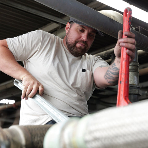 Technician performing industrial piping installation for compressed air system setup